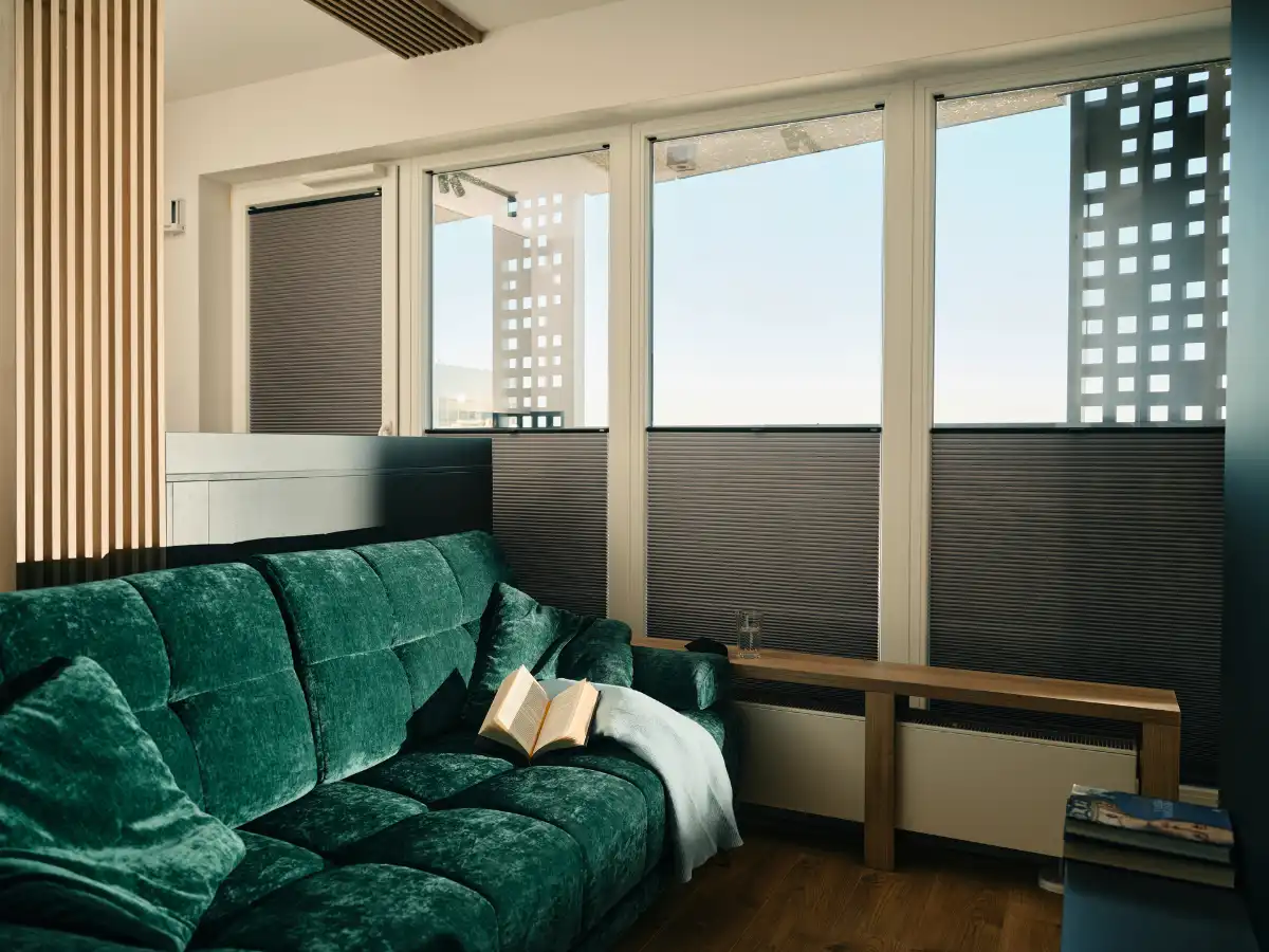 Wohnzimmer mit Plissees an den Fenstern Gemütliches Wohnzimmer mit grünem Samtsofa und modernem Fensterdesign