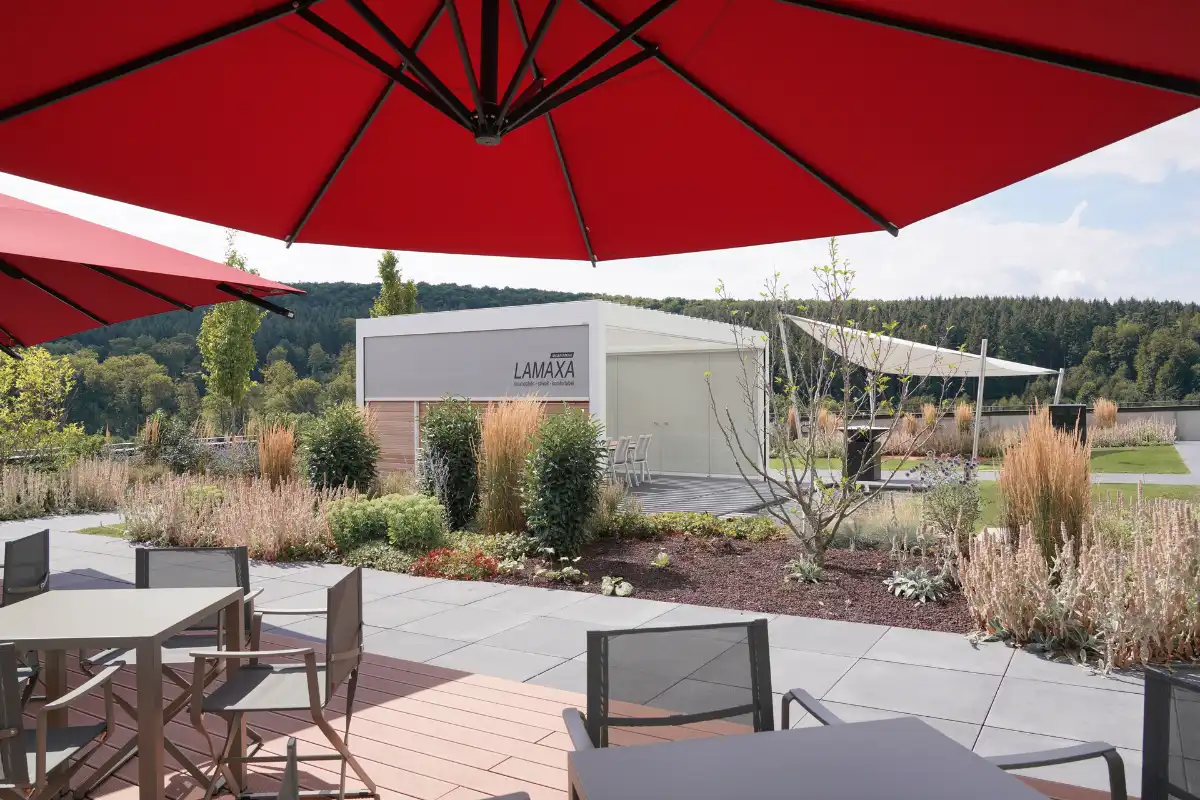 Stilvolle Terrassengestaltung mit Lamellendach und Sonnenschirm Moderne Gartenlandschaft mit Lamaxa Terrassenüberdachung und roten Sonnenschirmen