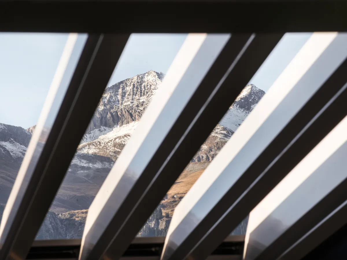 freistehendes Lamellendach mit einer Glasfassade Blick auf einen Berg durch Lamellen